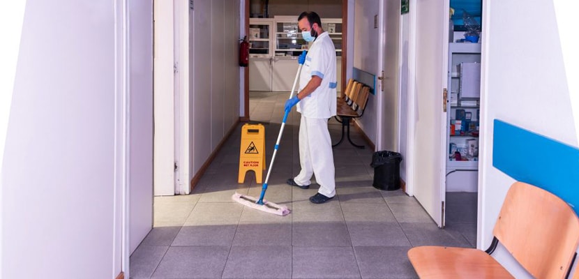 Empleado de aseo limpia piso de corredor de hospital