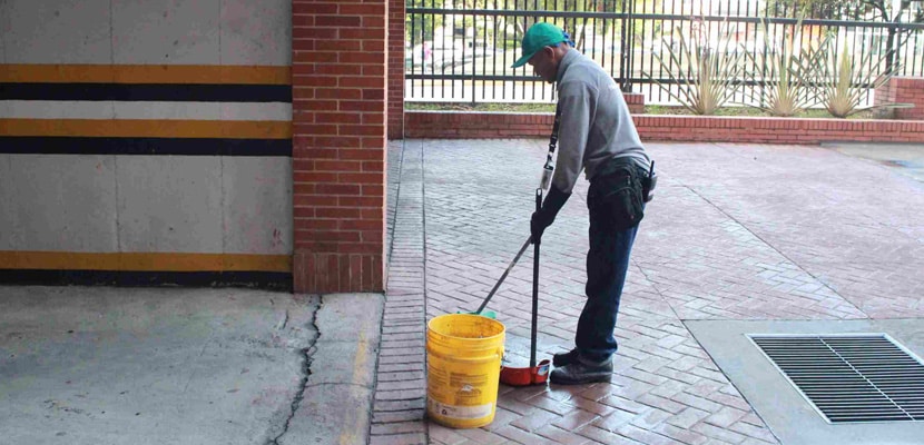 Personal masculino recoge residuos después de barrer un parqueadero