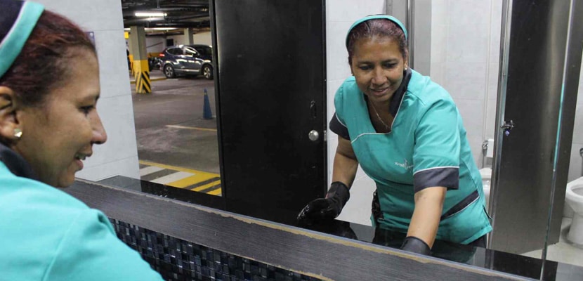 Trabajador realiza limpieza de fachada con trapero mientras es supervisado