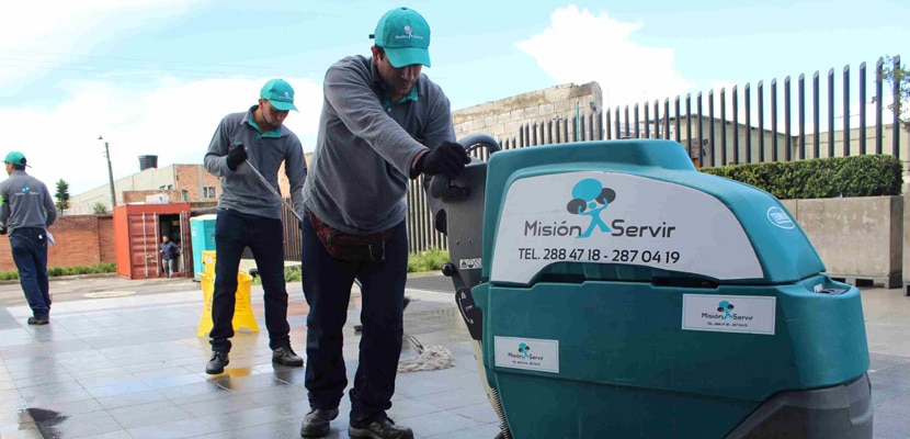 Personal de limpieza limpia piso de área perimetral de bodega