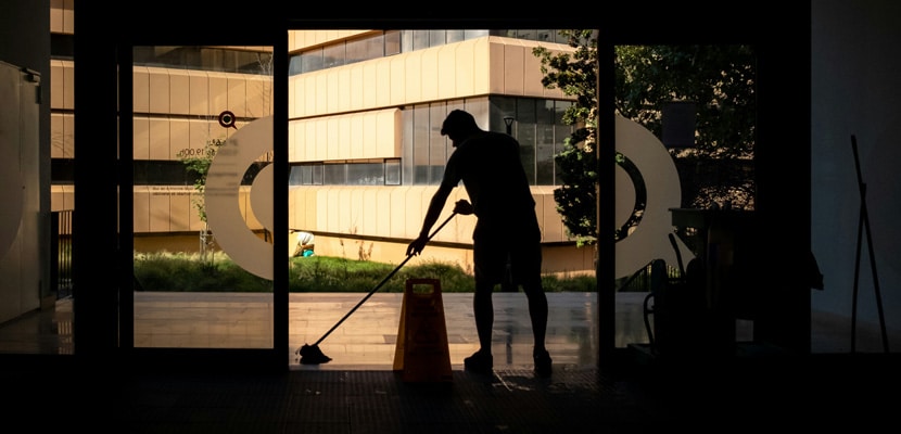 Hombre realizando aseo en la entrada de un edificio mostrando el aseo para empresas con Misión Servir