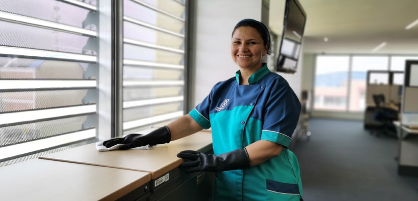 Experta en servicio de aseo oficinas Bogotá realizando limpieza en mesa