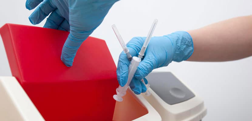 Plano cerrado de persona desechando jeringas utilizadas en una caneca mostrando como se clasifican los residuos hospitalarios con Misión Servir