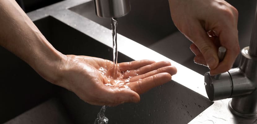 Plano cerrado de persona abriendo la llave de un lavamanos mostrando el ahorro de agua en empresas contratando a Misión Servir outsourcing de aseo
