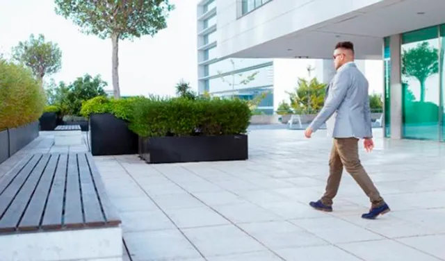 Hombre de negocios camina por un espacio al aire libre de un parque empresarial